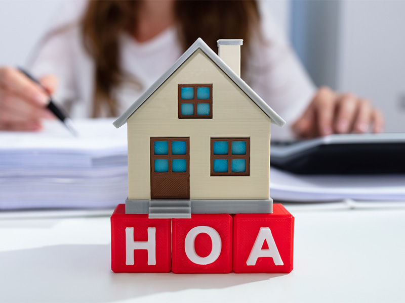 Image of a toy house in front of a girl writing on a book